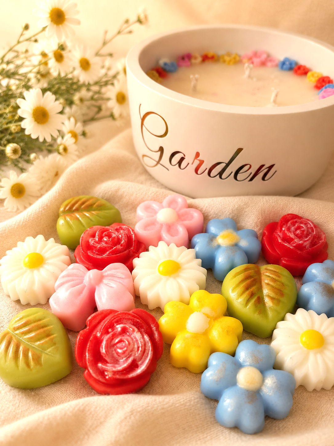 Bombones de cera en forma de flores de colores con vela aromatica de fondo