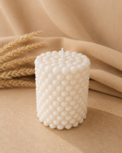 Vela decorativa en forma de pequeñas perlas con fondo neutro