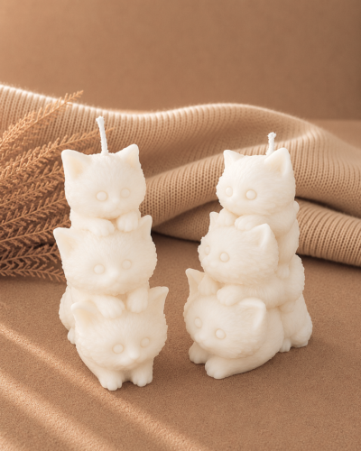 vela decorativa en forma de gatos apilados con fondo neutro