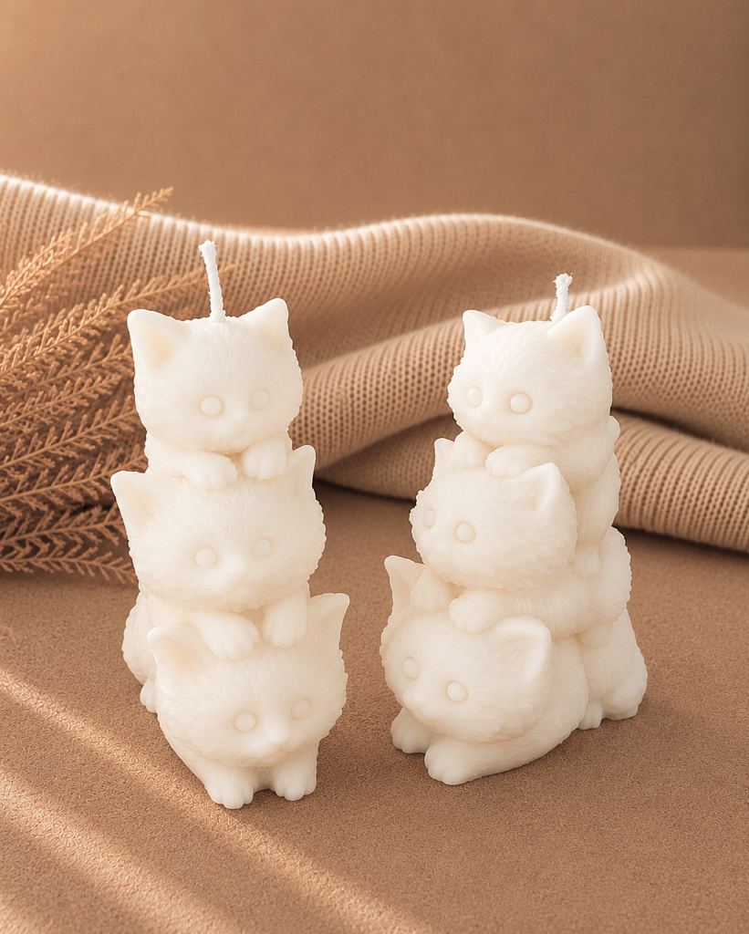 vela decorativa en forma de gatos apilados con fondo neutro